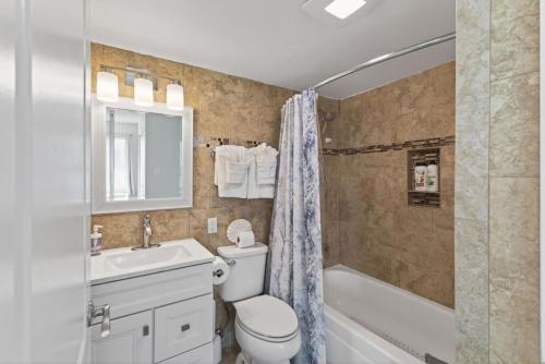 a bathroom with a toilet and a sink and a tub at New / Oceanfront Beach Condo, Pool, Gym, Fishing in Virginia Beach