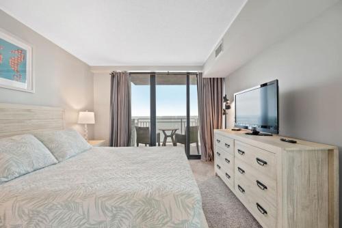 a bedroom with a bed and a flat screen tv at Oceanfront Condo/ Pool/ Surfing/ Fishing / EW 1002 in Virginia Beach