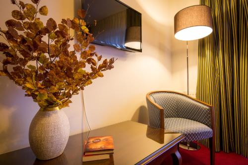 a room with a table with a vase and a chair at Hotel Boutique Belvedere in Sinaia