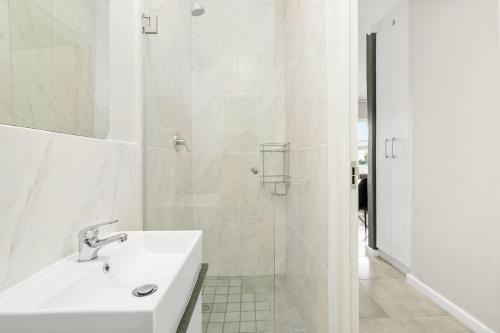 a white bathroom with a sink and a shower at The Orion 16 in Table View