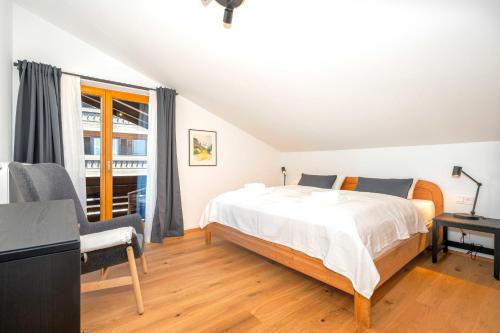 a white bedroom with a bed and a window at Ferienwohnung Dorfmitte in Reit im Winkl