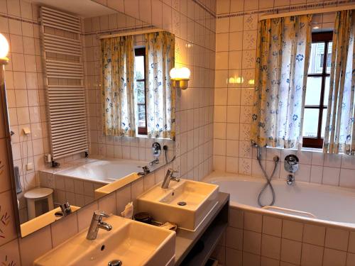 a bathroom with two sinks and a tub at Hotel-Restaurant & Metzgerei Rößle in Dettingen an der Erms