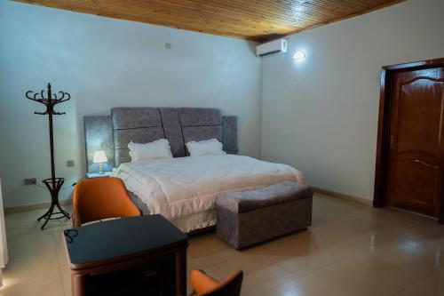 a bedroom with a bed and a chair and a television at Kaze Consolidate Home Inn in Kigali