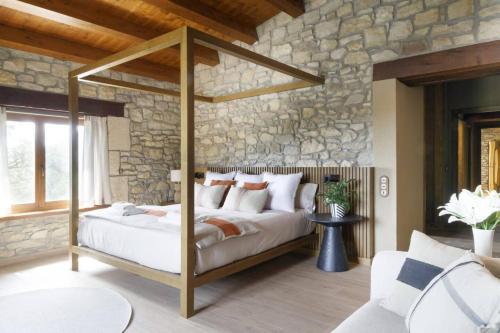 a bedroom with a bed and a stone wall at Villa Mas Summit in Collsuspina