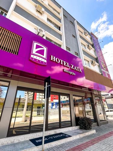 a building with a purple sign on the front of it at Hotel Zata e Flats in Criciúma