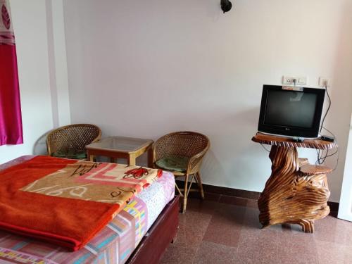 a bedroom with a bed and a tv on a table at Rose Cottage in Devikolam