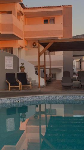 a swimming pool with chairs and a building at Coralli Beach Hotel in Kokkini Khanion