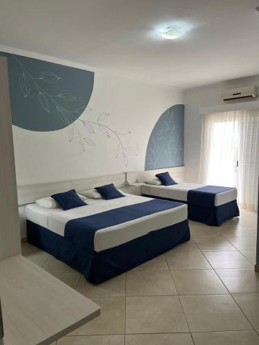 two beds in a bedroom with blue and white at Hotel do Feijão in Cachoeira Paulista