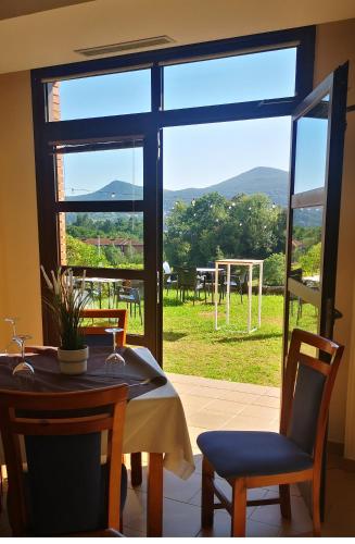 a dining room with a table and chairs and a large window at Hotel Ibaigune in Murueta