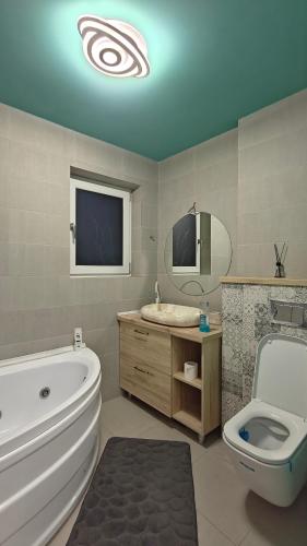 a bathroom with a tub and a toilet and a sink at Ultracentral Piata in Caracal