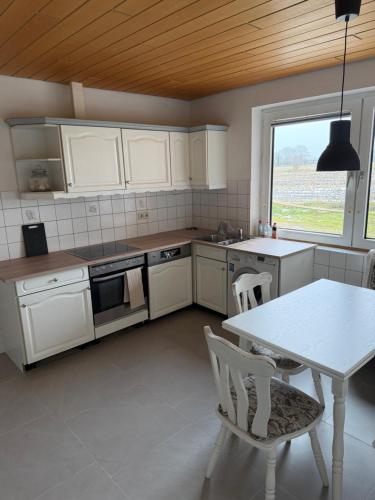 a kitchen with white cabinets and a table and a window at Ferienhaus Arlewatt in Arlewatt