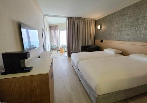 a hotel room with two beds and a television at Vert Dead Sea by AFI Hotels in Ein Bokek