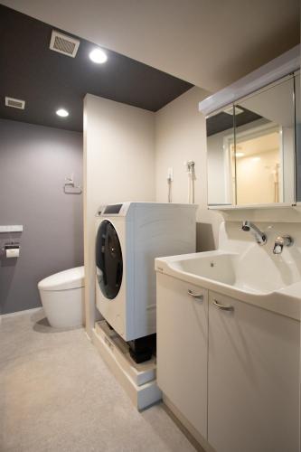 a bathroom with a toilet and a sink with a washing machine at NIYS apartments 56type in Tokyo