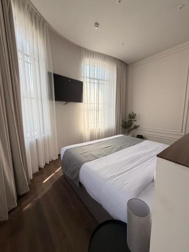 a bedroom with a large bed with white sheets and windows at Vista Catedral Guadalajara - Self Check in in Guadalajara