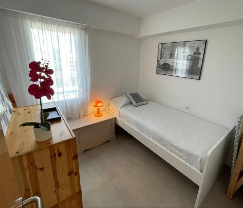 a bedroom with a bed and a desk with a vase of flowers at Apartamento Terraza Mar in Malgrat de Mar