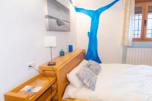 a bedroom with a bed with a blue tree on the wall at Casa Rural Mirabueno in Cuenca