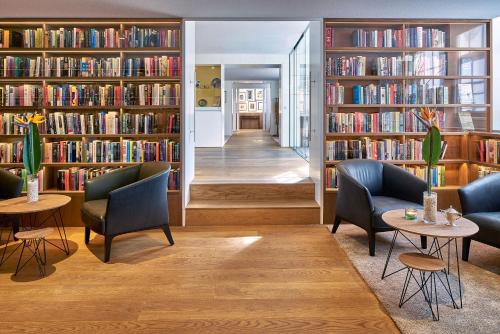 une bibliothèque avec deux chaises, deux tables et des étagères dans l'établissement Ambassade Hotel, à Amsterdam