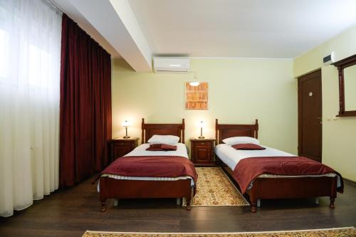 two beds in a room with red curtains at Vila Roma in Deva