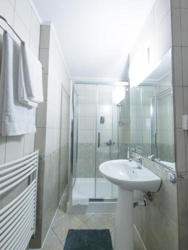 a white bathroom with a sink and a shower at Vila Roma in Deva