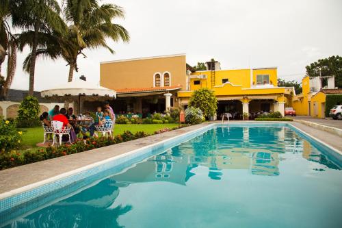 a swimming pool in front of a house with people sitting at Hotel La Loma Tepic in Tepic