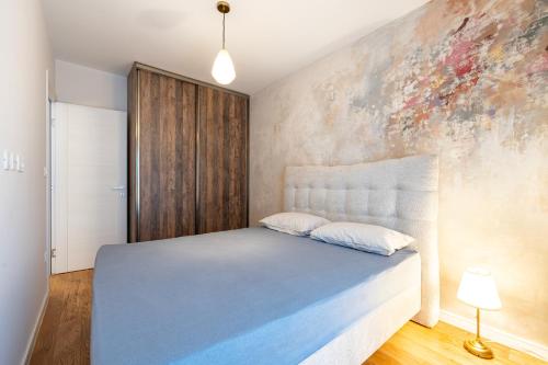 a bedroom with a bed and a painting on the wall at Fratello Apartment in Podgorica
