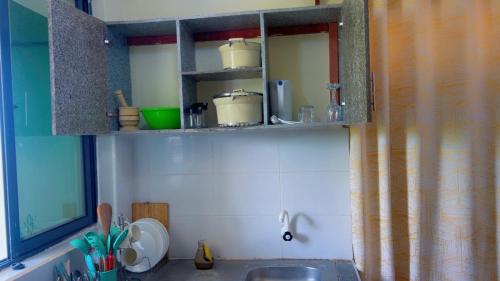 a kitchen with a sink and a shelf with pots and pans at Figtree 1bedroom by kiv in Kilifi