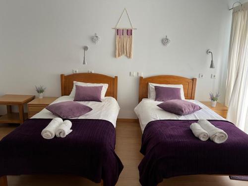 two beds in a room with purple sheets and pillows at Casa Miná in Montalegre