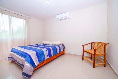 a bedroom with a bed and a chair and a window at Newly renovated apartment with pool in Santa Cruz Huatulco