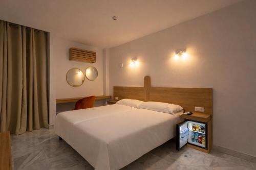 a bedroom with a large white bed and two mirrors at Hotel El Tujjar in Los Barrios