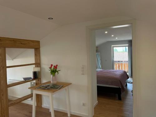 a bedroom with a bed and a table with flowers on it at Charmantes Dorf-Apartment in Dietramszell