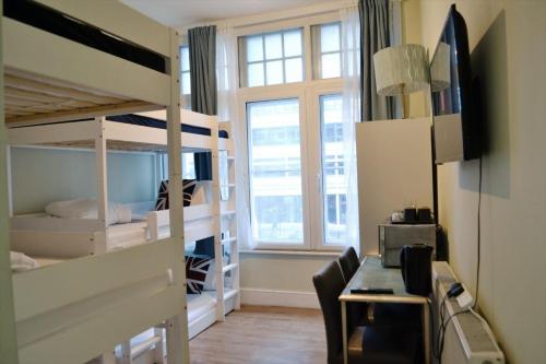 a dorm room with bunk beds and a desk and a table at Perfume Warehouse Stay in London
