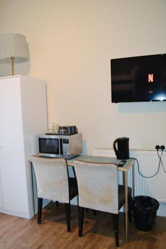 a kitchen with a table with two chairs and a microwave at Perfume Warehouse Stay in London