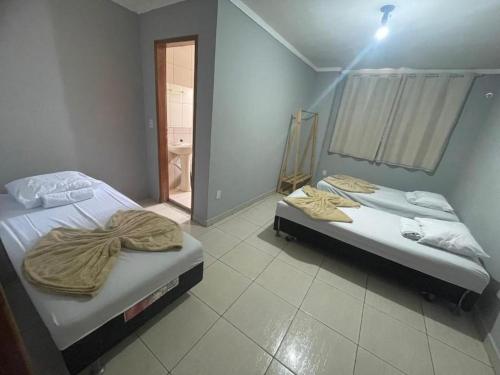two beds sitting in a room with a window at Hotel Universo in Goiânia