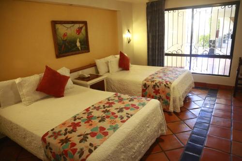 a hotel room with two beds and a window at Hotel La Loma Tepic in Tepic