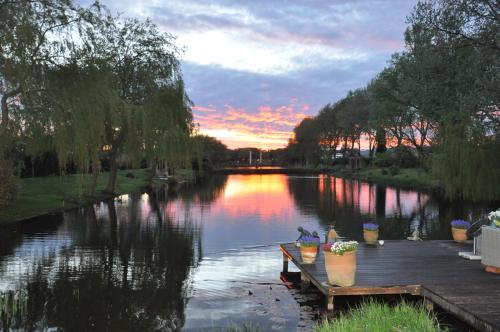 a view of a river at sunset with flowers on a dock at Paradijs Eiland in Hillegom