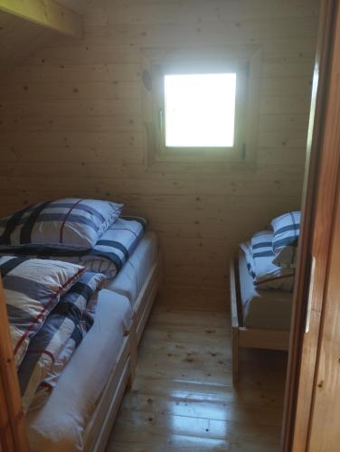 two beds in a log cabin with a window at Perła Brenno in Brenno