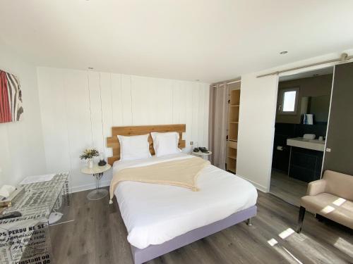 a bedroom with a large white bed and a chair at Hotel Napoleon in Île dʼAix