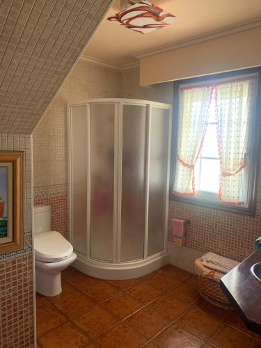 a bathroom with a shower and a toilet and a window at Lar do Pero - Ribeira Sacra in Tioira