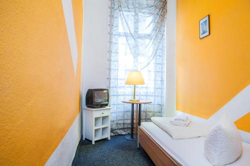 Habitación pequeña con cama y TV. en Hotel-Pension Insor, en Berlín