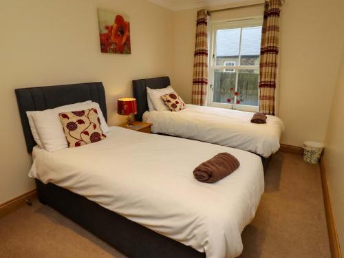 two twin beds in a room with a window at West Gate in Embleton