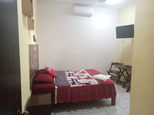 a small bedroom with a bed and a table at Casa Corozo in Bacalar