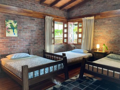 a bedroom with two beds and a brick wall at Morada de las Aves in Cali