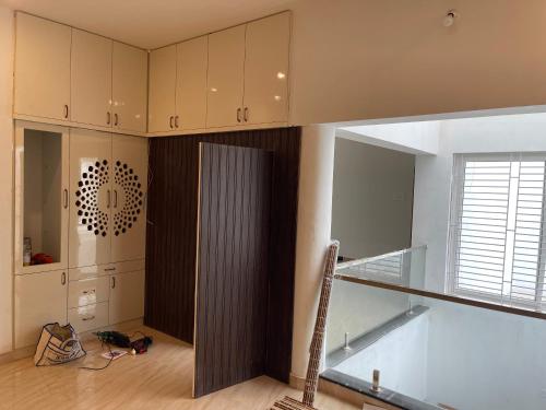 a kitchen with white cabinets and a glass staircase at Santhosh Villa in Thanjāvūr