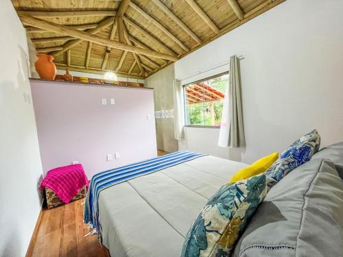 a bedroom with a bed in a room with a window at Chalé Flor de Ypê in Carrancas