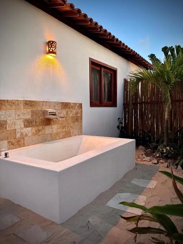 a large white bath tub sitting outside of a house at Chalé Caju Knots in Parajuru