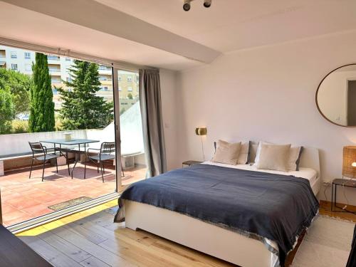 a bedroom with a bed and a table and a balcony at Suite privativa em apartamento em Algés, Lisboa in Algés