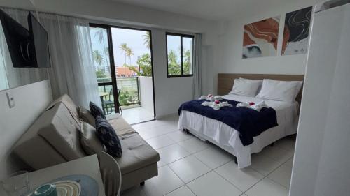 a bedroom with a bed and a couch and windows at Mana Experience Muro Alto in Porto De Galinhas