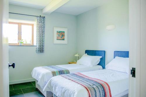 two beds in a white room with a window at 3 Bed in Loddiswell oc-t34185 in Churchstow