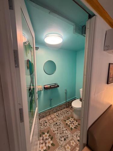 a bathroom with a toilet and a blue wall at Kaneng Homestaykohpu in Ban Klang