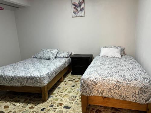 a bedroom with two beds and a night stand with a bedskirts at Casa Altamirano in Chilpancingo de los Bravos
